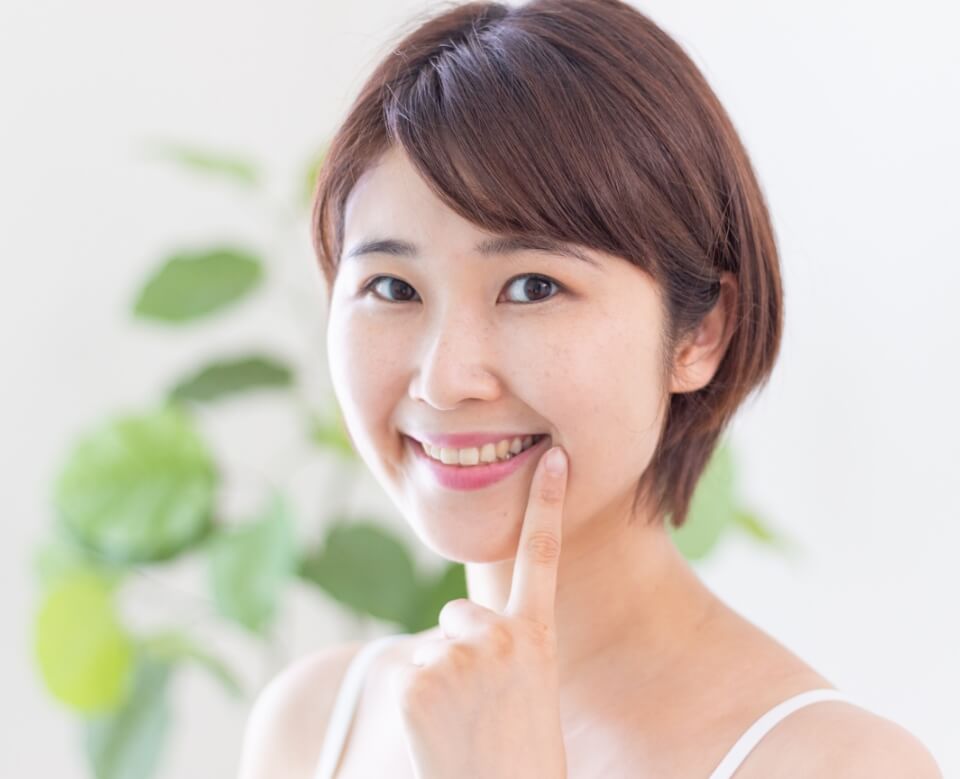 Woman pointing to healthy smile after gum disease treatment