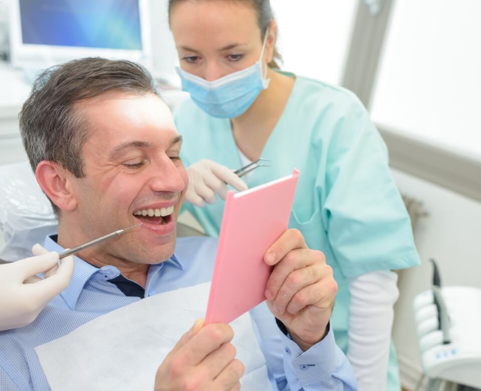 Man looking at smile after restorative dentistry treatment